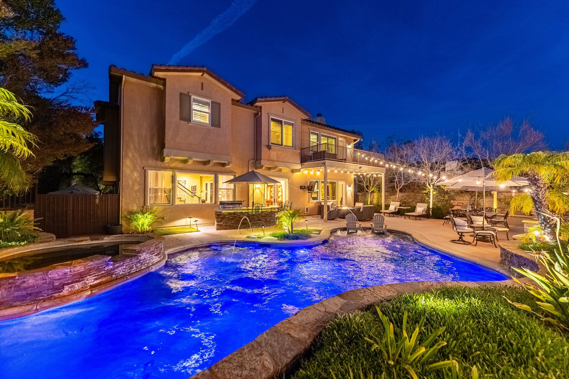 Twilight view of the pool with the home illuminated